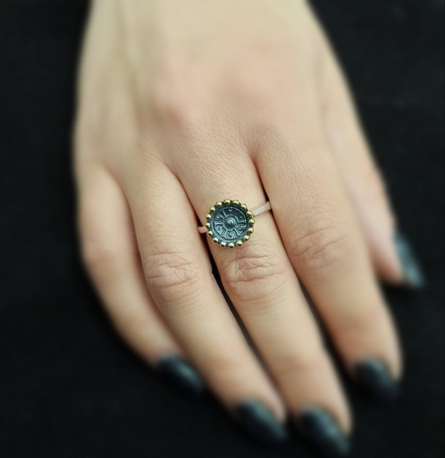 Дамски сребърен пръстен с основен елемент вдлъбнат кръг с орнаменти и оксидация, покрайчен с месингови точки.